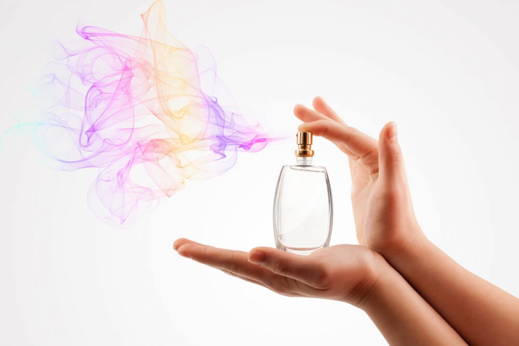 Una mano presionando un frasco de perfume.