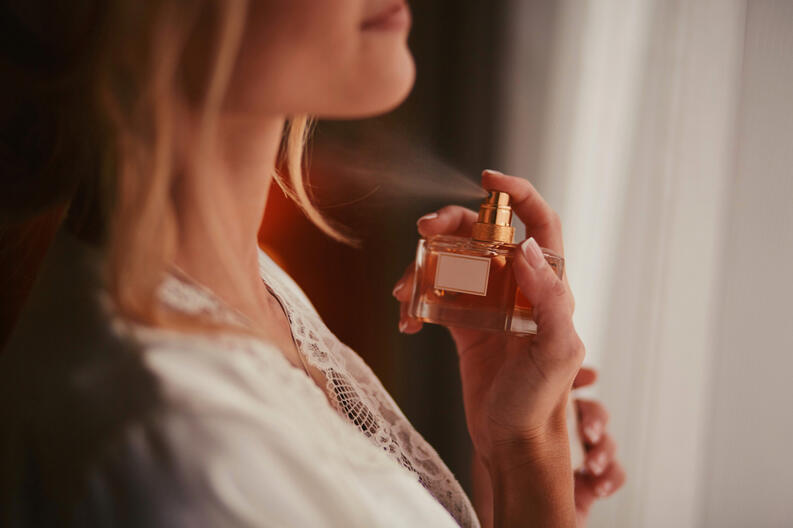 Mujer aplicándose perfume crperfumes